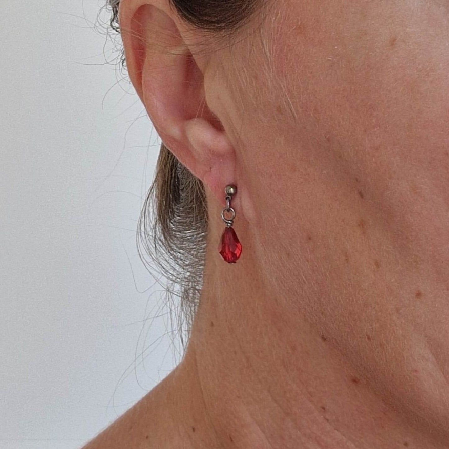 Titanium Stud Earrings with Dangling Ruby Red Crystal Teardrops Shown on Ear