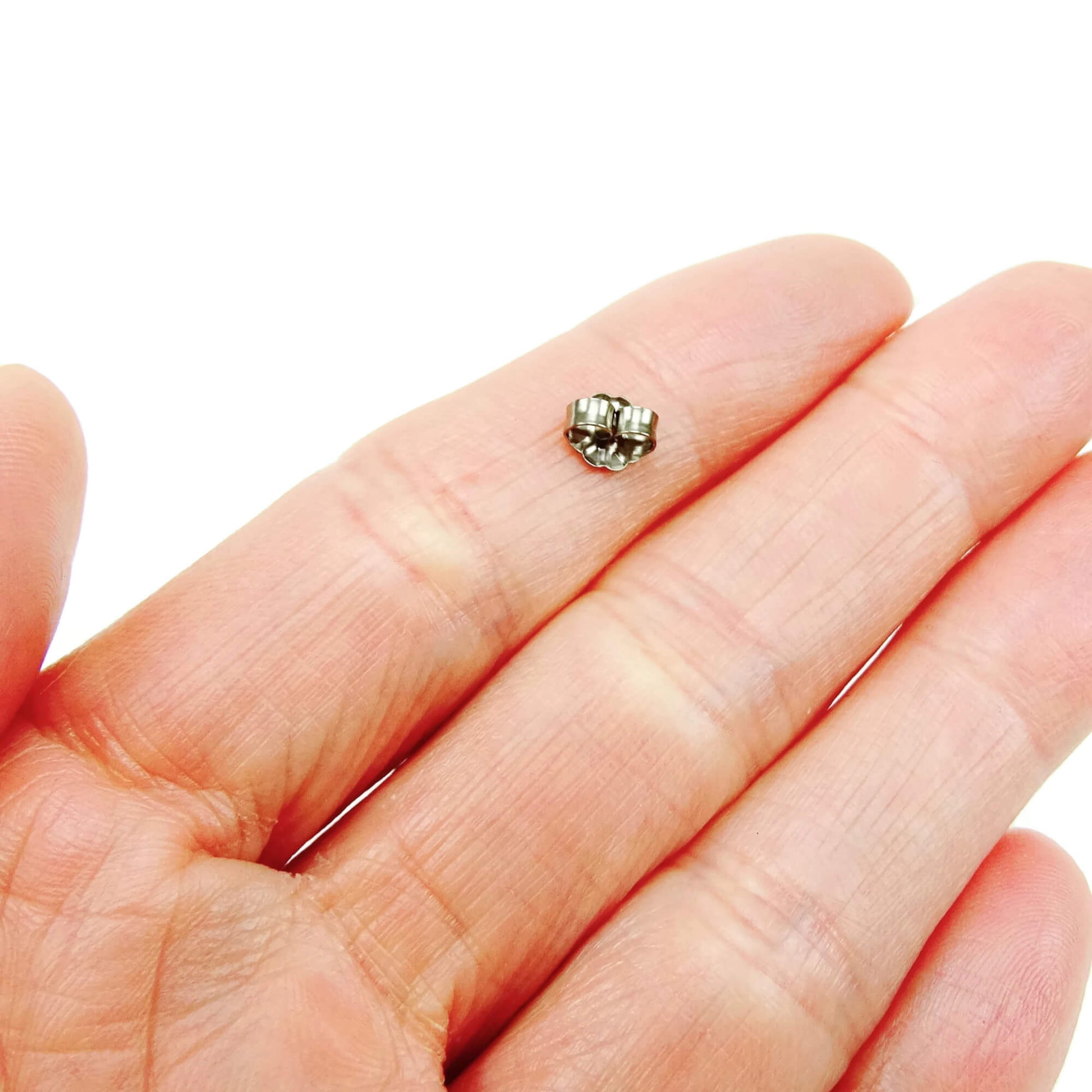 hypoallergenic titanium earring back shown on hand for size reference