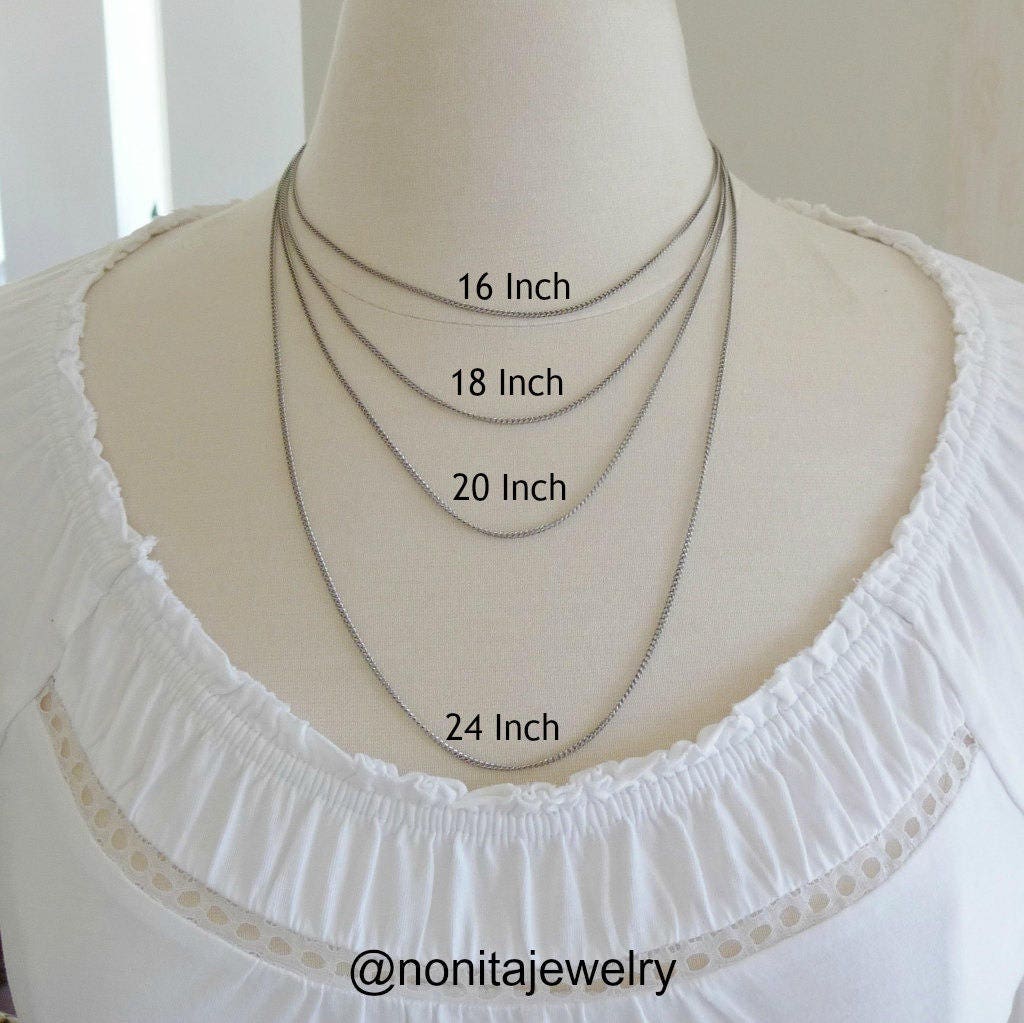 A mannequin wearing a white blouse with different titanium chain lengths displayed on it.