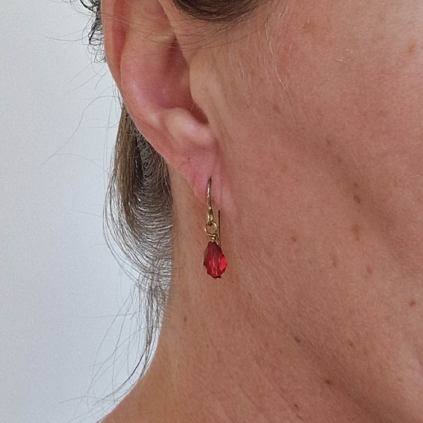 Gold Titanium Earrings with Ruby Red Crystal Teardrops Shown in Ear