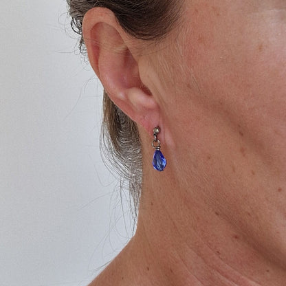 Titanium Stud Earrings with Dangling Sapphire Blue Crystal Teardrops Shown on Ear