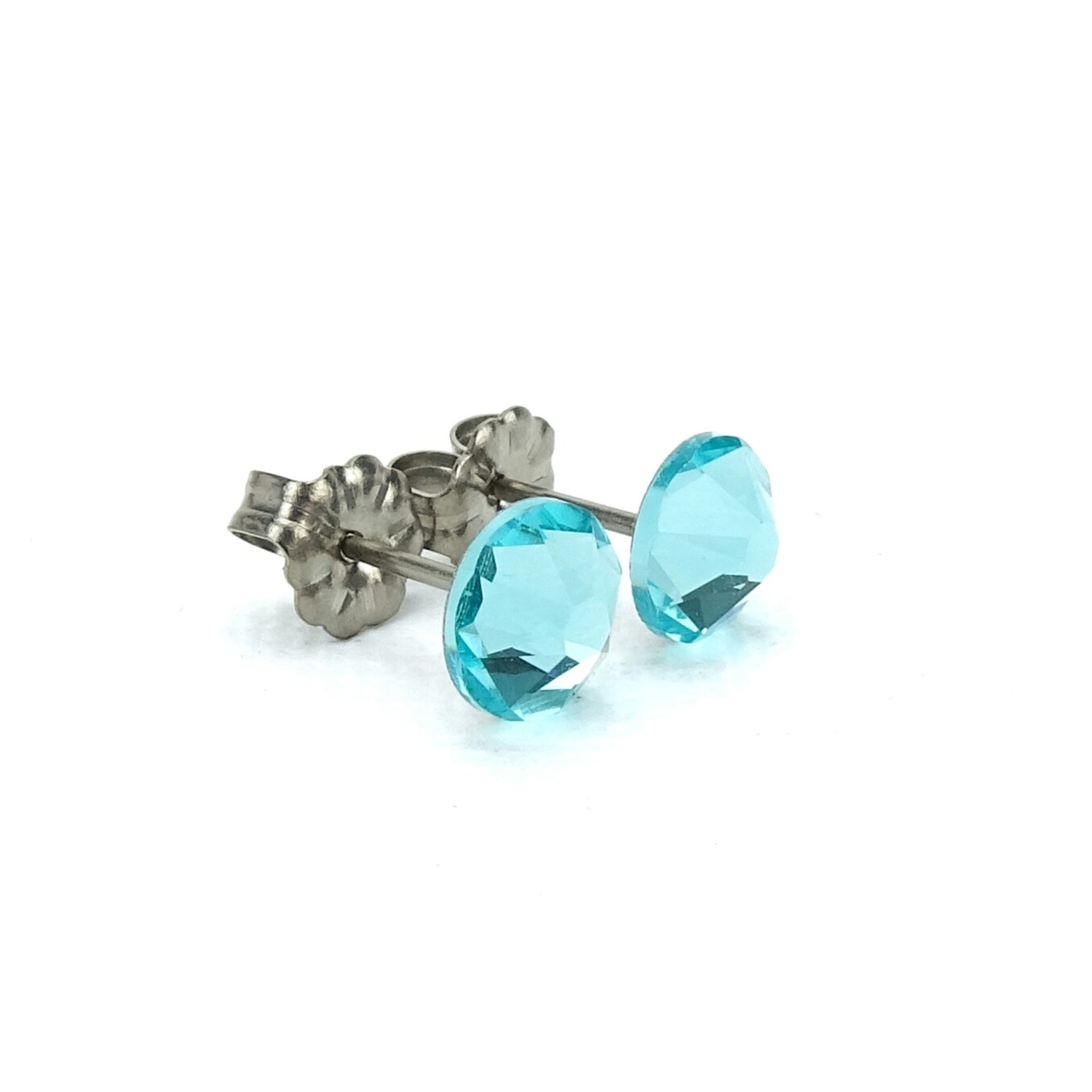 A pair of turquoise-colored earrings with silver metal posts and fluted backings.